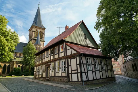 Fachwerkhaus mit Kirchturm an einer gepflasterten Straße