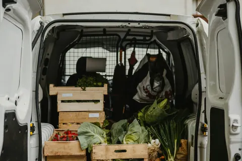 Lieferwagen mit Holzkisten voller Gemüse und Erdbeeren
