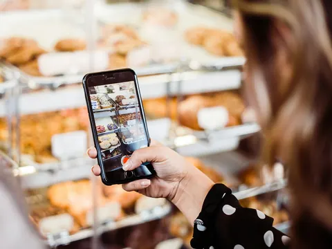 Smartphone fotografiert die Gebäckauslage einer Bäckerei